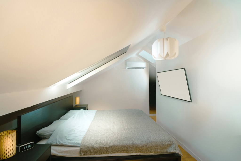 Dormitorio luminoso bajo cubierta, con techo inclinado y ventana en el tejado