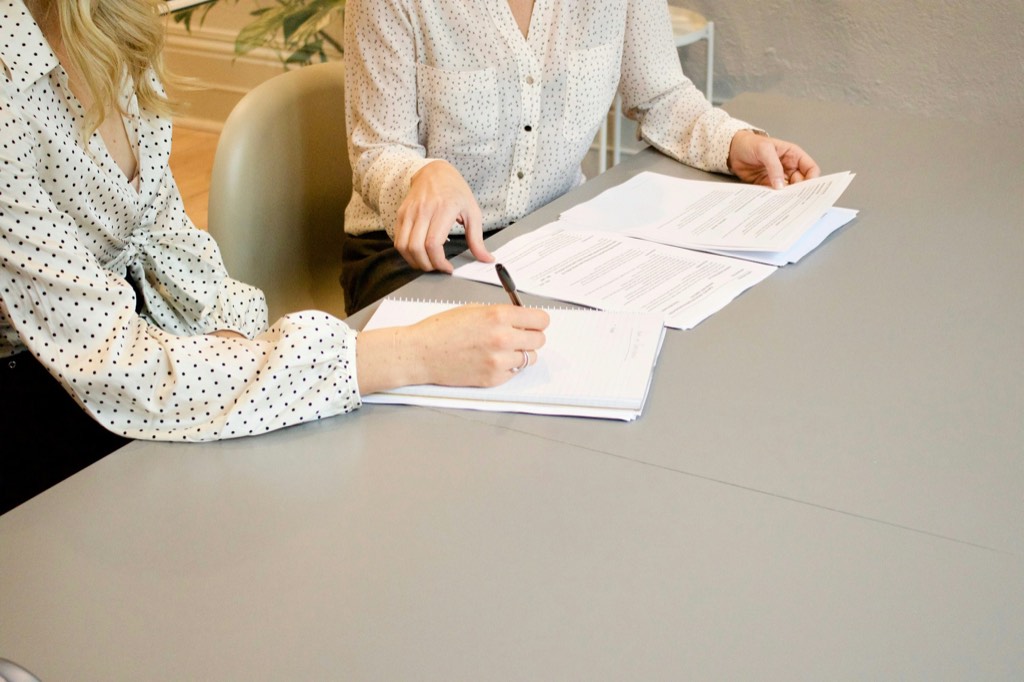 Dos personas revisando y firmando documentación sobre una mesa