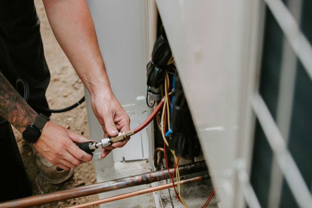 Técnico conectando una manguera de servicio a la unidad exterior de un equipo de climatización